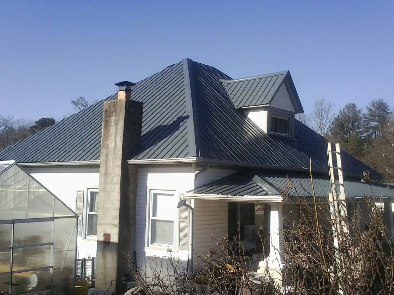 Dark blue standing seam metal roof on a white farmhouse with dormer — Slate & Tile Roof Repair by Roofing Brothers in Wrens