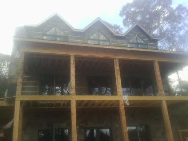 Dormers and porch framing on a large log home under construction — Roof Coating work by our crew in Wrens