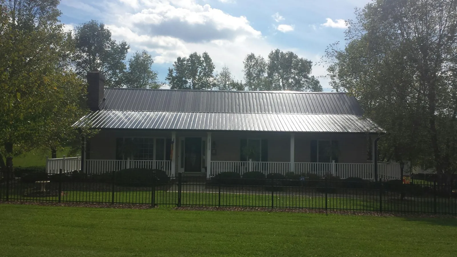Gray metal roof on a brick ranch with a full width front porch — Gutter Guard Installation work by our crew in Wrens