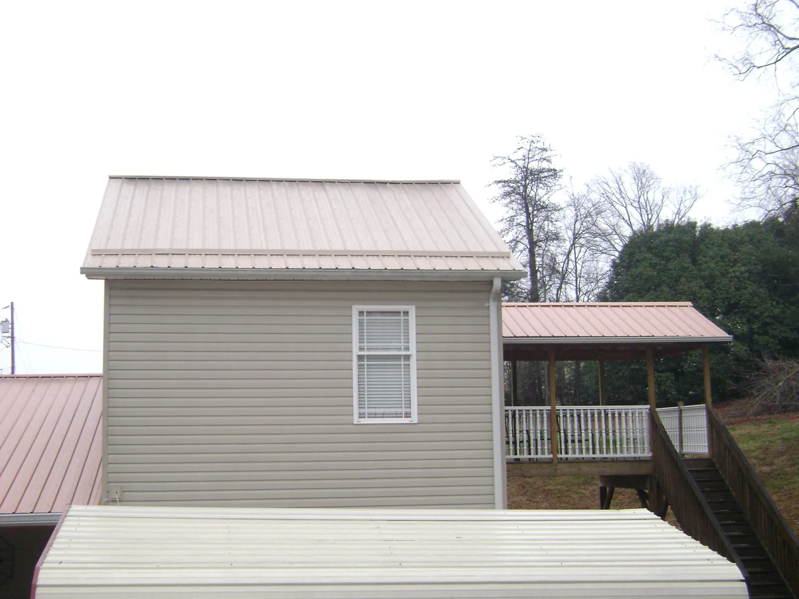 Tan metal roofs on a two story addition and attached porch, from a Roof Replacement job in Wrens