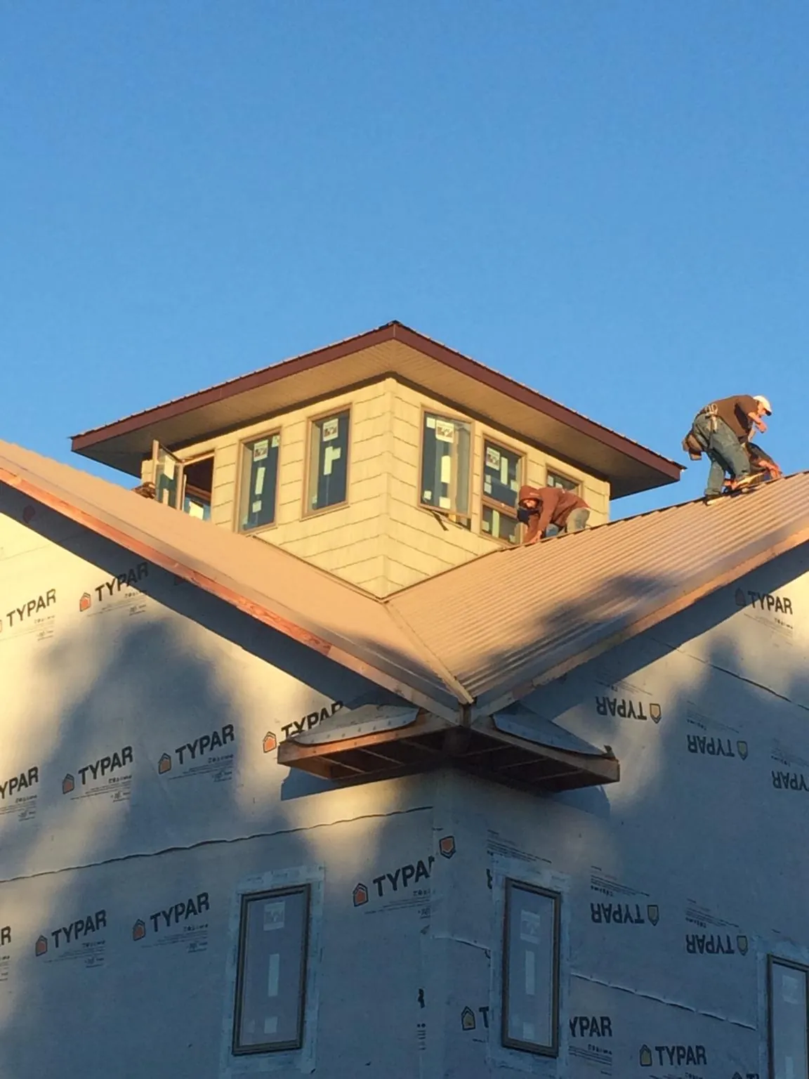 Roofers working around a rooftop cupola on a new metal roof at sunset — Roof Waterproofing in Wrens by Roofing Brothers